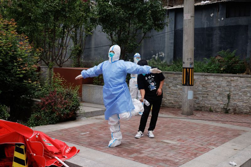 三月以來上海、北京等地爆發本土新冠疫情，衝擊大陸經濟。圖為北京核酸檢測站的工作人員在消毒。（路透）
