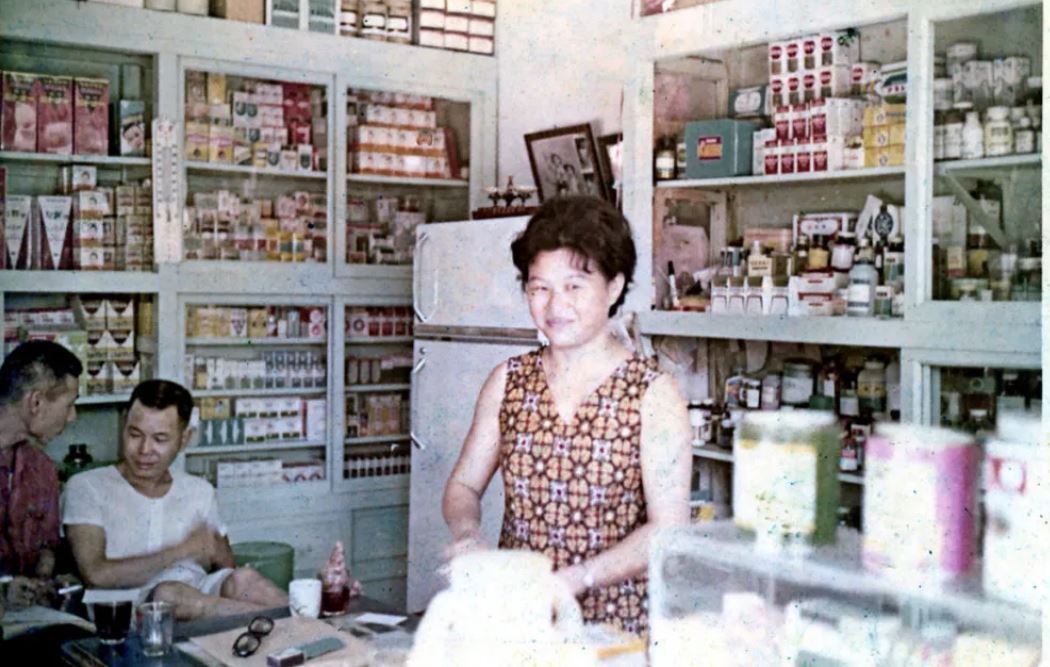 七星藥局第二代藥師吳嘉文的母親（中）站在現今已很難找到的傳統木藥櫃前。（吳至鎧提...