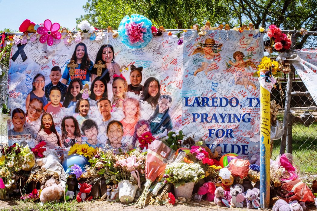 羅伯小學外，槍擊案受害者的海報以及哀悼花束、玩偶。 圖／法新社  