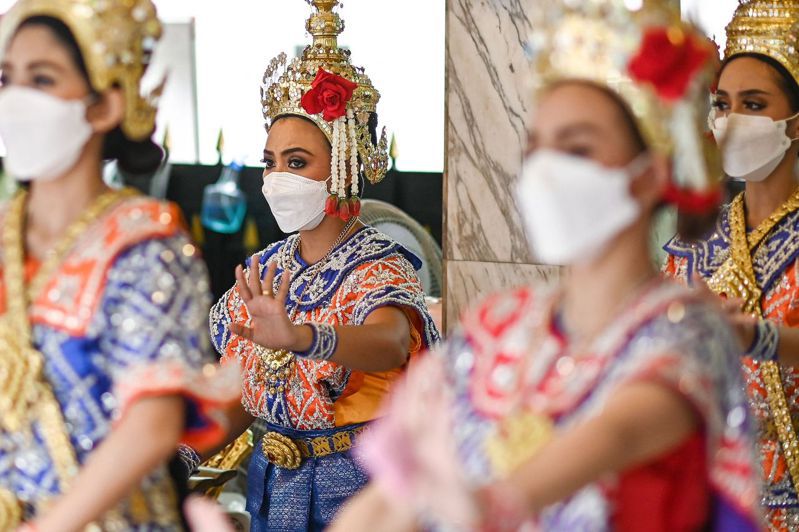 曼谷四面佛佛壇的傳統舞者24日戴口罩表演。（法新社）