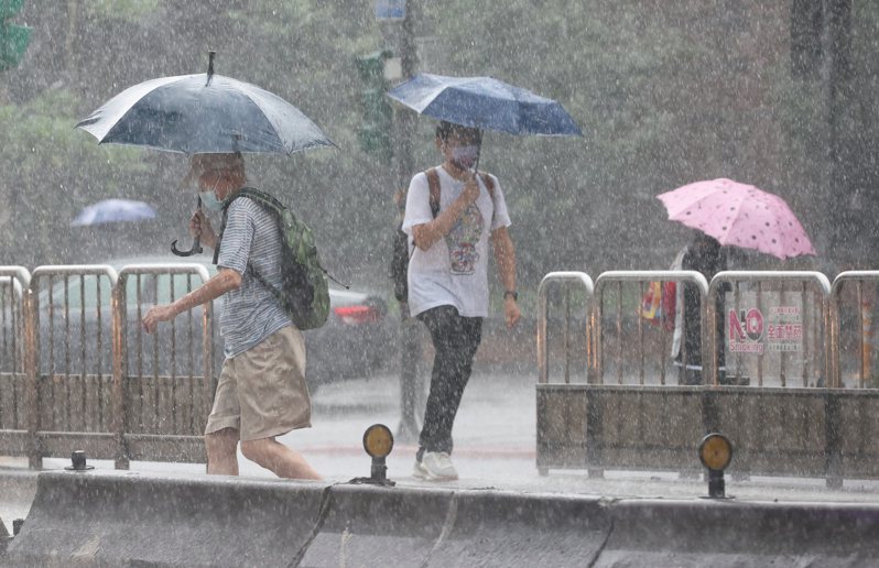 台北市下午下起大雷雨，路上行人撐著傘快速過馬路。圖與文／潘俊宏