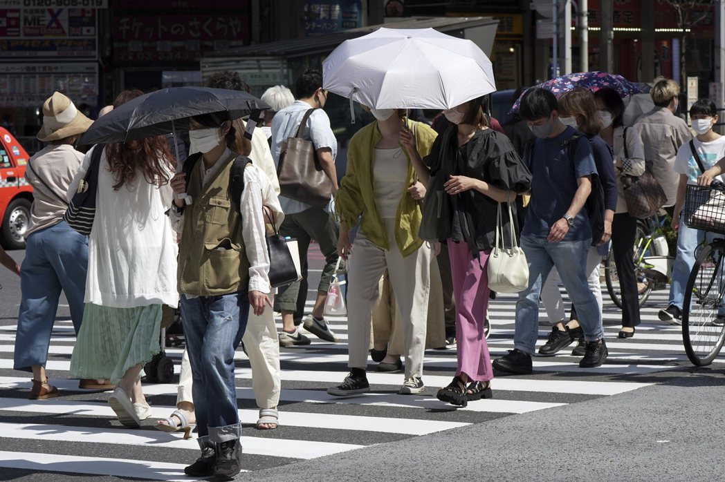 日本東京民眾今年5月30日在烈日下撐傘經過街頭。美聯社