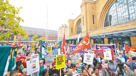 英國抗議群眾25日在倫敦國王十字車站外高舉標語並聲援鐵路工人的罷工行動。（美聯社）