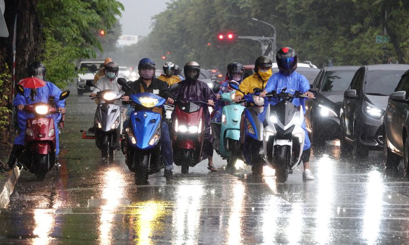 高雄傍晚突降大雷雨，騎士在雨中紛紛穿上雨衣騎車。記者劉學聖／攝影