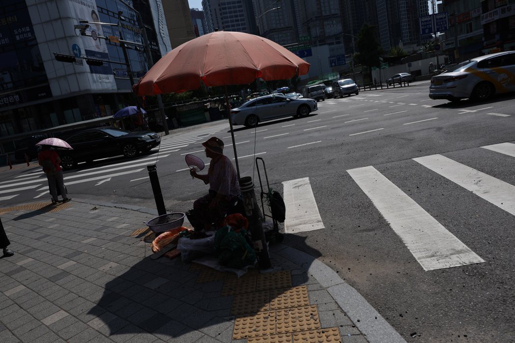 南韓連日出現高溫天氣，首爾一名街頭小販3日不停揮舞扇子幫自己降溫。歐新社