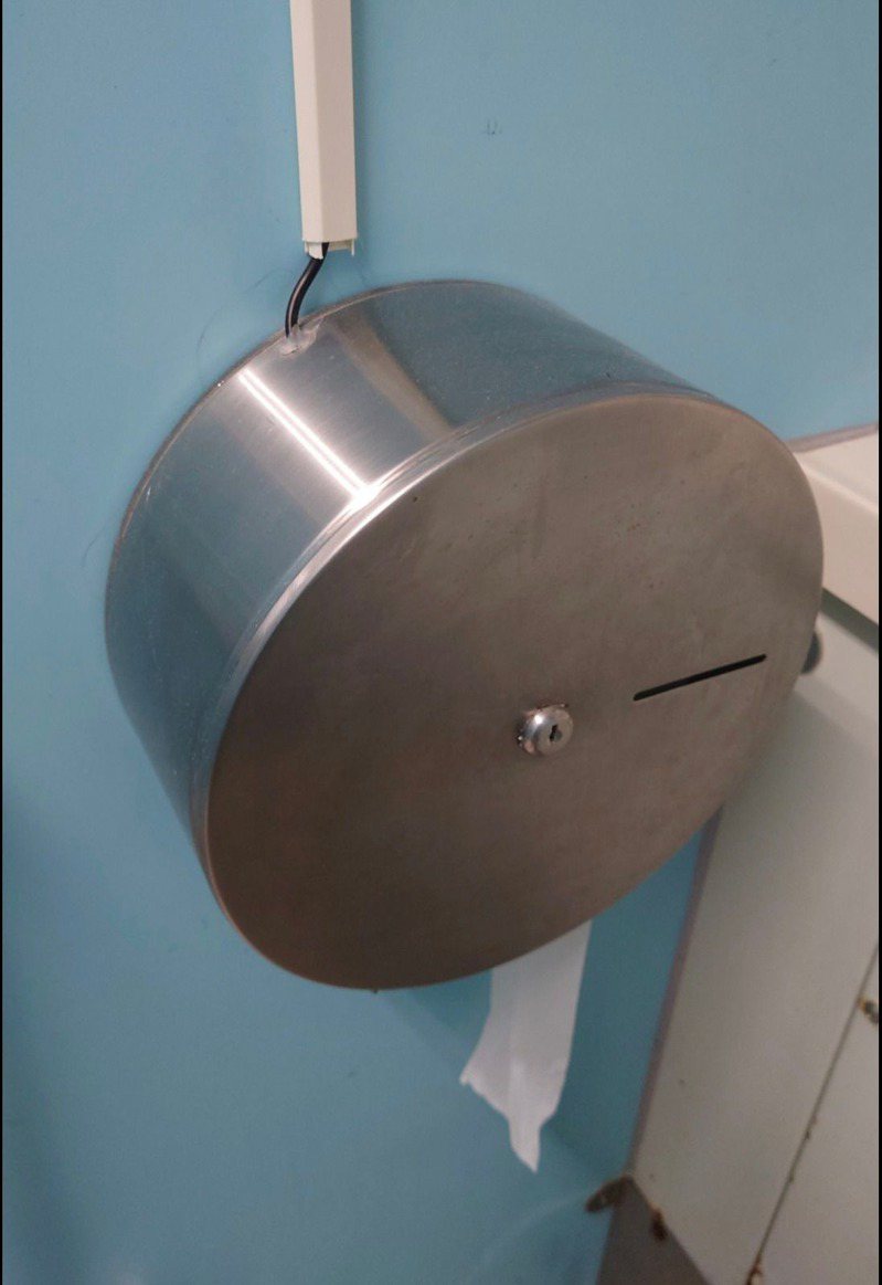 日前一名男網友在外上廁所時，發現滾筒衛生紙架的上方竟連接著一條黑線，不禁好奇為何會有這樣的設計。 圖／翻攝自臉書社團「路上觀察學院」