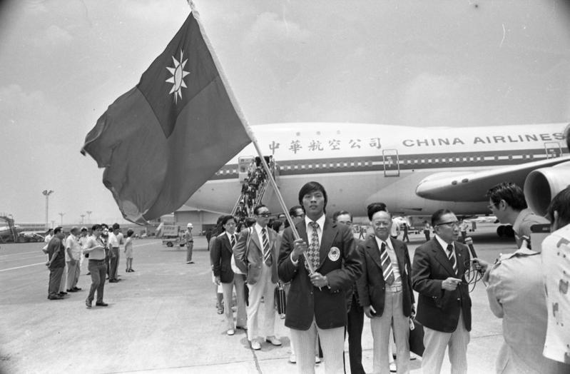 參加第21屆奧運會的我國代表團1976年7月19日提前返台，田徑隊員陳進龍(中)高舉國旗在軍樂聲中率領團員下機。 圖／聯合報系資料照片