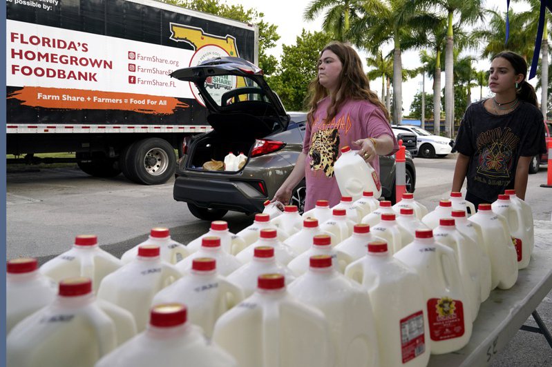 美國佛州邁阿密一間食物銀行的人員發放牛奶給排隊領取的民眾。不少美國民眾受不了通膨壓力，在各地食物銀行前排隊領取食物。美聯社