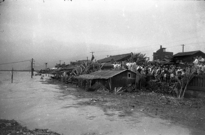1956年8月1日，萬達颱風掃台，台北市部分低窪地區淹水嚴重，大批民眾佇立於橋頭高處，無奈地觀看浸泡於水中的家園。 圖／聯合報系資料照片