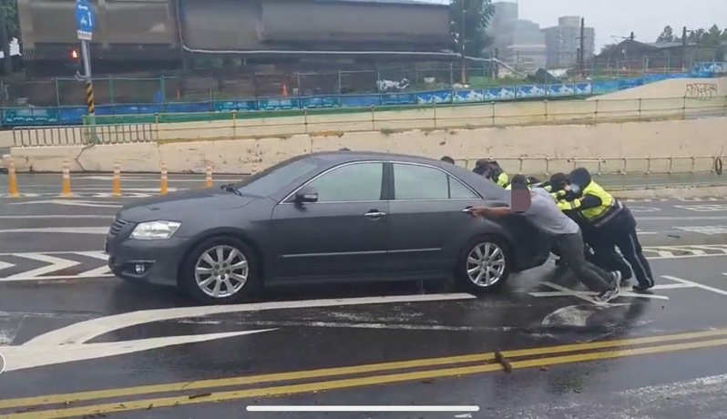 台南市警員協助將卡在小東路地下道的轎車推離淹水區。記者黃宣翰／翻攝