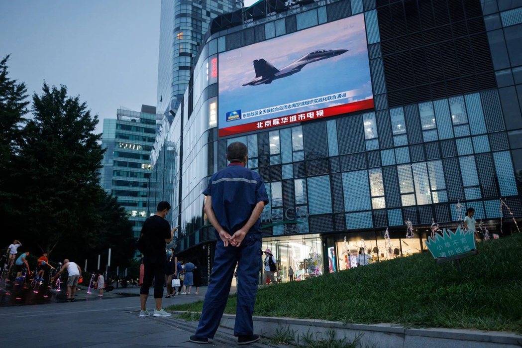 北京街頭的大螢幕上，中國央視播放了據稱是中國戰機在台灣附近飛行的畫面。 圖／路透...
