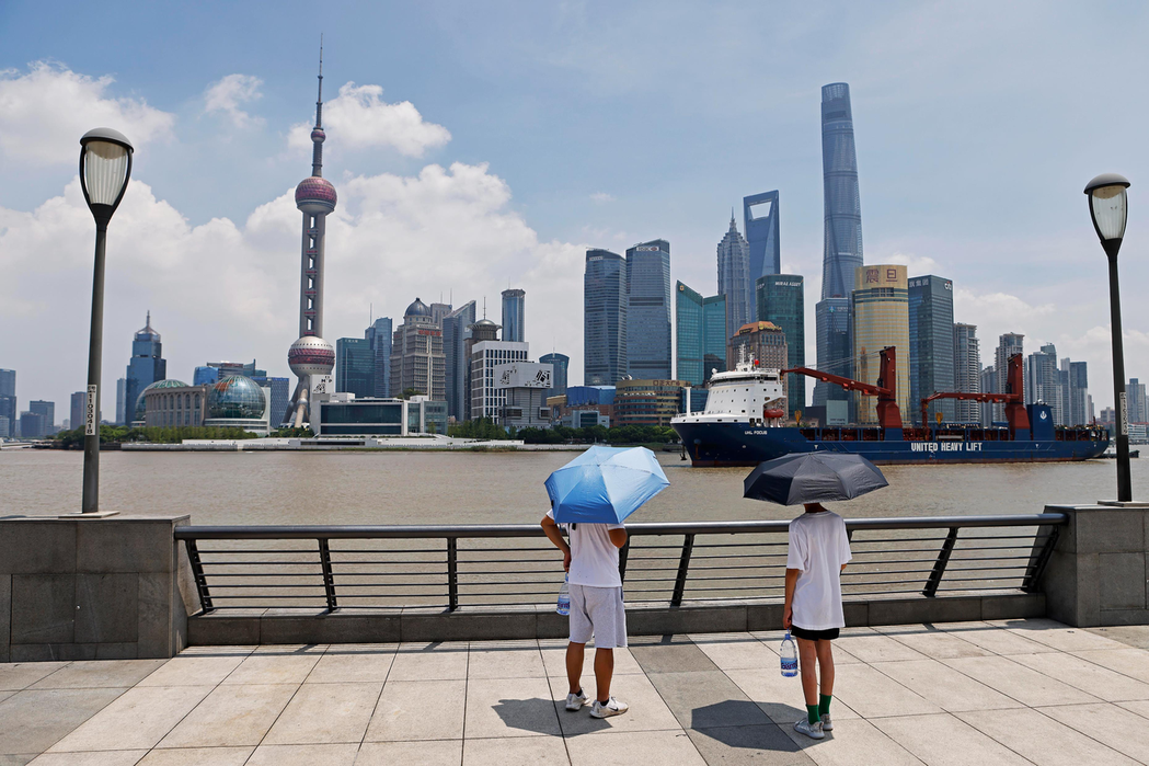 上海今年夏天酷熱難耐。圖為日前在外灘濱江步道上，遊客除了提一大罐礦泉水，還得撐傘...