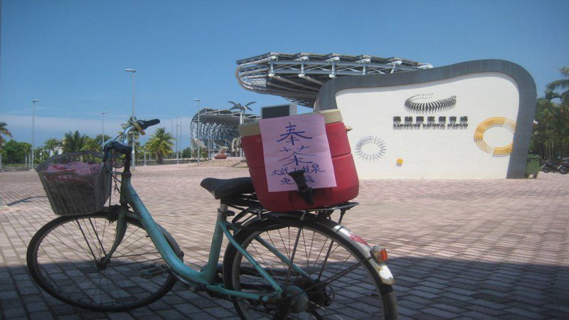 高雄世運體育場附近偶爾有位阿嬤騎腳踏車載桶開水上面寫「奉茶」二字，供路過口渴的人喝水。圖／張重玖提供