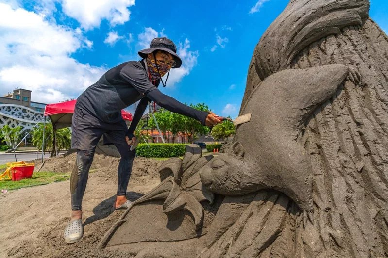2022八里城市沙雕展8月13日開展，沙雕師正投入雕刻創作「親吻花語」。 圖／新...