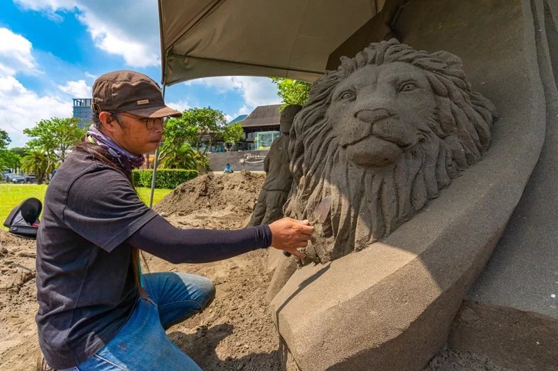 2022八里城市沙雕展8月13日開展，沙雕師創作出將從沙雕中跳出的生動獅子。 圖...