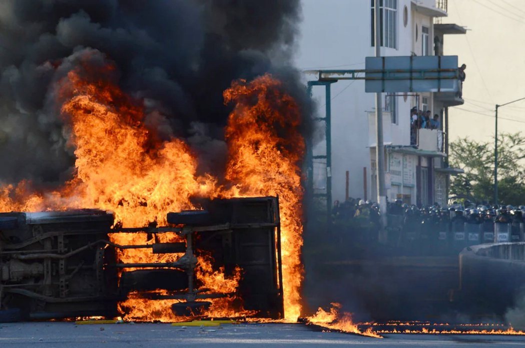 墨西哥民眾年復一年抗議伊瓜拉學生失蹤案，圖為抗議民眾在鎮暴警察面前點燃一輛汽車。...