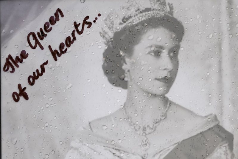 英國女王伊麗莎白女王二世8日駕崩，倫敦市民在白金漢宮大門前擺上女王年輕時的照片致意，懷念這位「贏得民心的女王」，照片上的雨滴有如人民哀悼的淚水。圖／美聯社