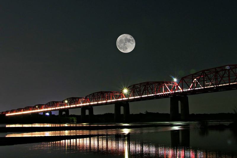 攝影師魏進福今年七月在濁水溪上的西螺大橋拍下大橋與月亮的合照，透過相機內建重覆曝光功能和遠近角度重覆拍攝，讓月亮看起來又大又圓。圖／魏進福提供