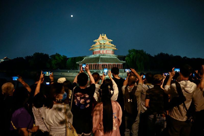 大陸多地疫情持續，北京民眾大多就地過節賞月。圖為九月十日，民眾在故宮角樓附近拍攝明月的景象。（法新社）