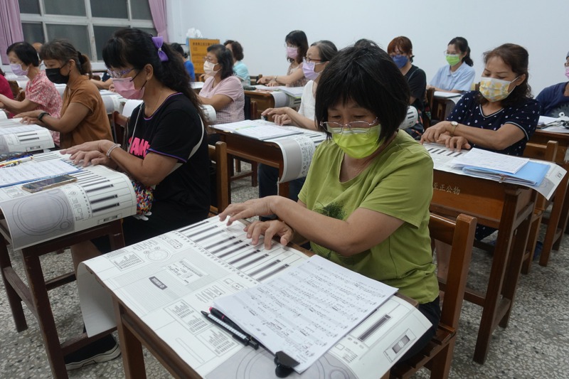 屏北社區大學鋼琴課的學員，使用紙鍵盤練習指法。記者劉星君／攝影
