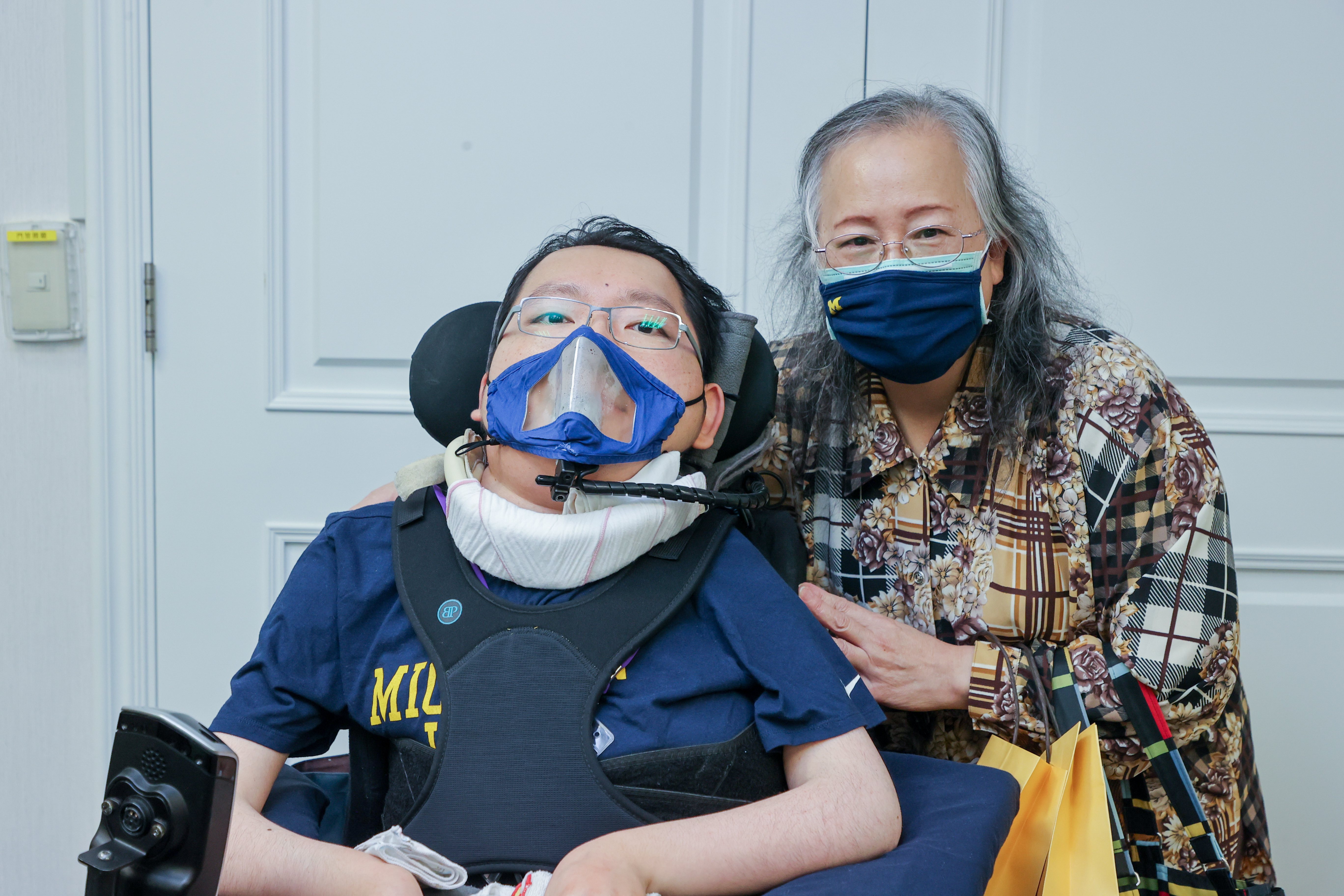 罕病SMA患者陳俊翰（左）與母親，陳俊翰上個月畢業於美國密西根大學回國，他身穿該校紀念T恤，母親也帶著該校紀念口罩。記者曾原信／攝影