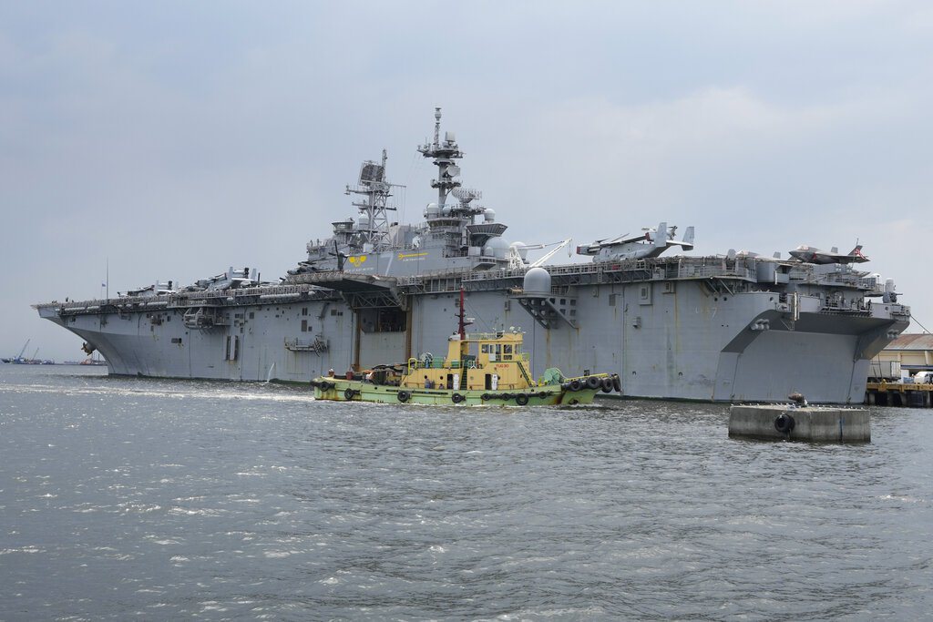 2022年9月27日在菲律賓馬尼拉的港口停靠期間，一艘拖船經過美國海軍的黎波里號航空母艦（LHA-7）兩棲攻擊艦。 圖／美聯社