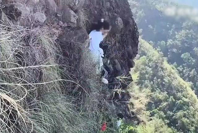 女生爬上了400米高的懸崖邊，困在上面無法動彈，要警方及消防聯合救援。（微博影片截圖）