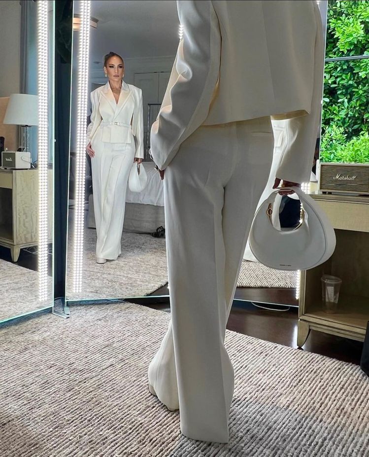 美國歌手Jennifer Lopez以一身俐落的全白西裝造型登場，搭配CHARLES & KEITH簡約彎月小流浪包。圖／CHARLES & KEITH提供