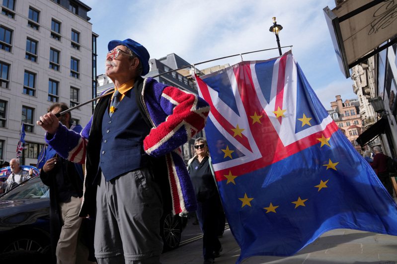「金融时报」指出，当前物价飞腾、投资与贸易低迷，其实源于脱欧效应。10月22日，一名抗议者在伦敦手持旗帜，唿吁英国重新加入欧盟。路透社(photo:UDN)