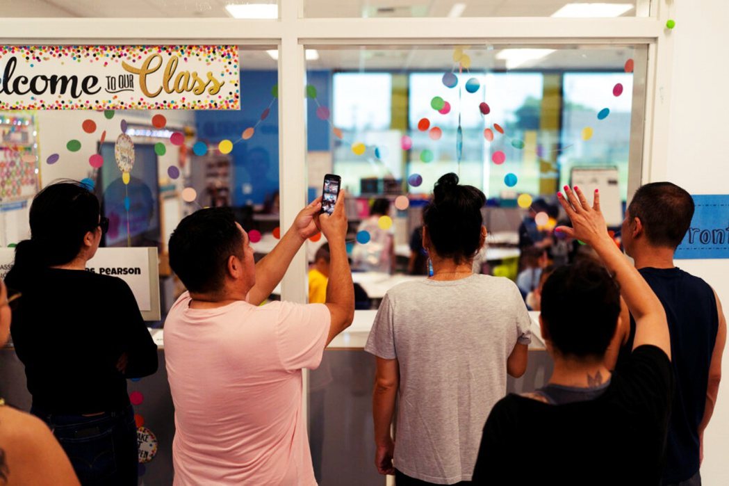 2022年8月是加州一所小學返校日的第一天，家長們聚集在課室外看孩子們上課。 圖...