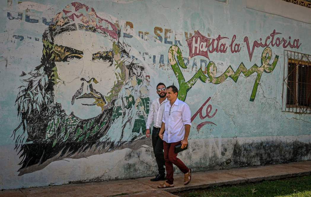古巴同婚合法後，一對同性伴侶從切格瓦拉畫像前走過。 圖／法新社