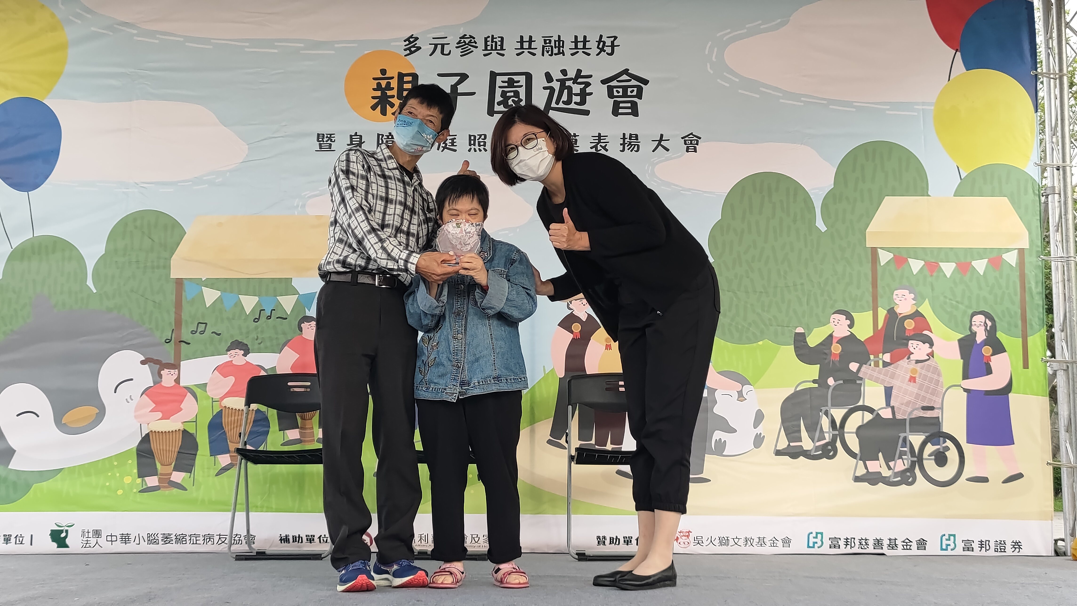 譚一民(左)今帶著唐寶寶王尤美(中)出席「多元參與共融共好」親子園遊會暨身障家庭照顧楷模表揚大會活動。