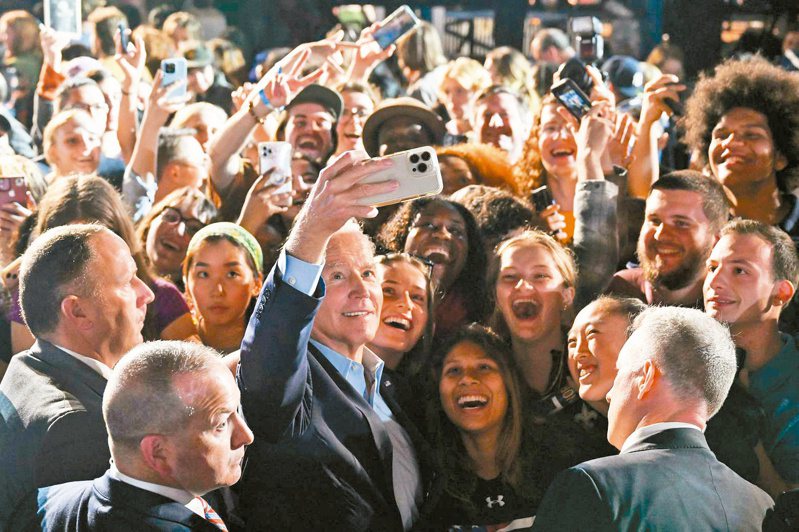 美國總統拜登（中）六日在紐約幫州長候選人霍楚站台，和支持者玩自拍。（法新社）