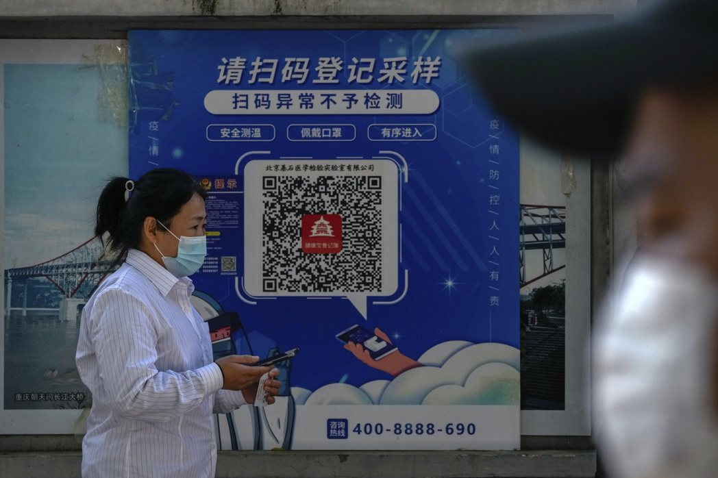 北京一名民眾走過要求掃健康碼的標示。 圖／美聯社