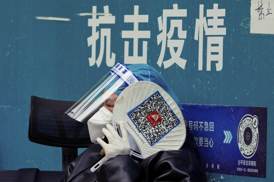 北京的一名防疫人員手持印有健康碼QR Code的扇子。 圖／美聯社