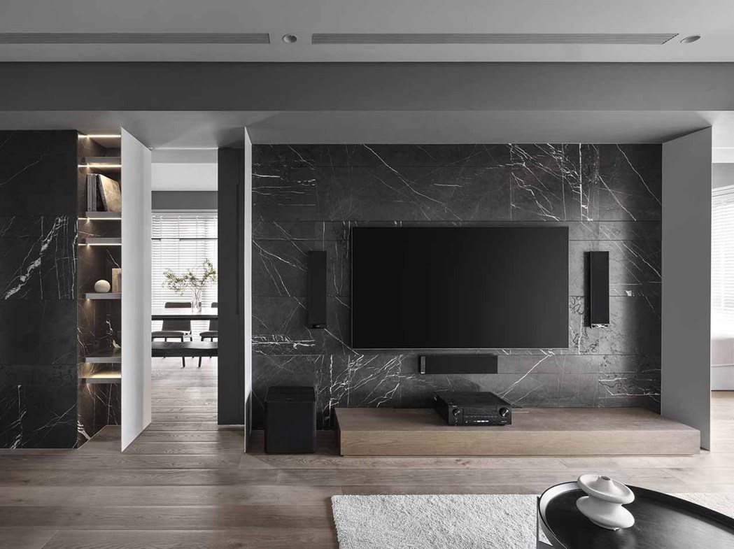 電視牆的黑色石材上，帶著豐富白色紋理，透過細節的變化塑造室內層次。