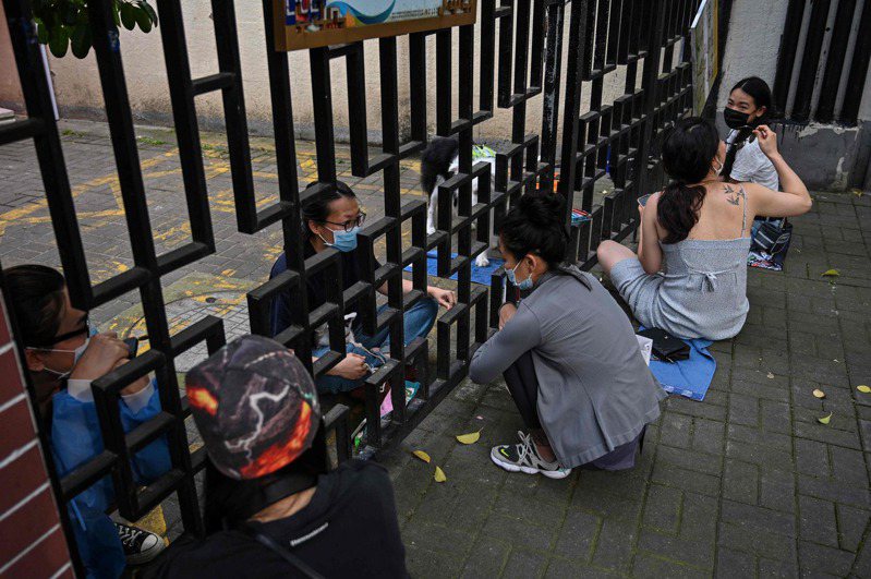 圖為上海封城時，靜安封控區內民眾隔著鐵欄聊天。法新社