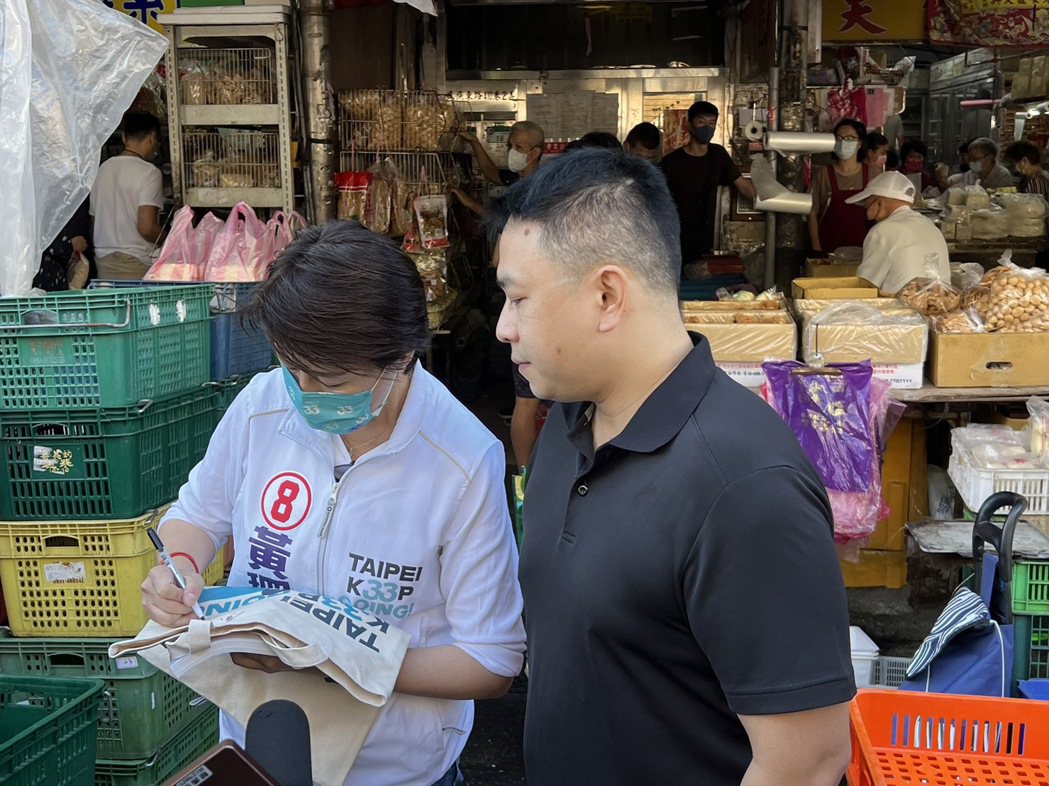 無黨籍台北市長候選人黃珊珊(左)今天到榮濱市場拜票，支持者拿出黃珊珊競選環保袋給...