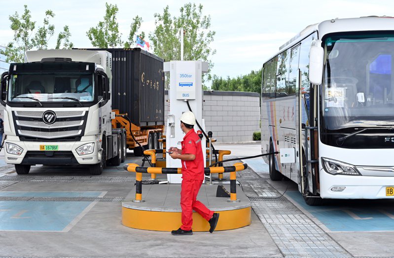 圖為北京大興國際氫能示範區，氫燃料客車（右）與氫燃料貨車在加氫站加注燃料。（中新社）