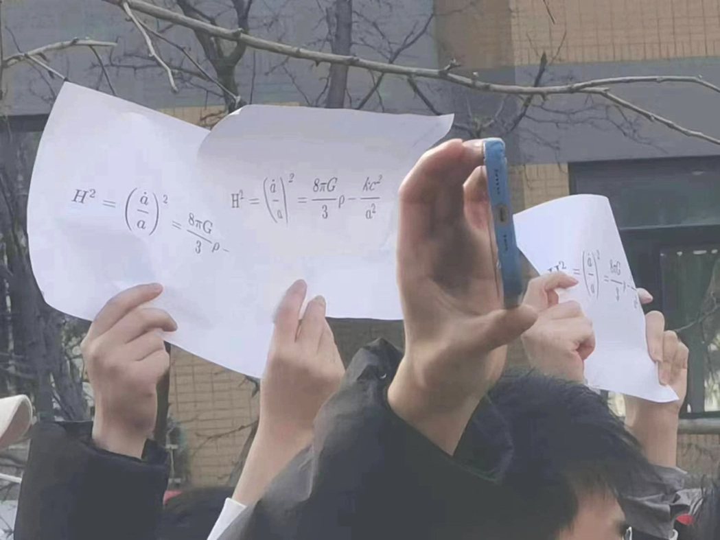 北京清華大學內，學生手舉寫著Friedmann方程式的白紙，取諧音「free的m...