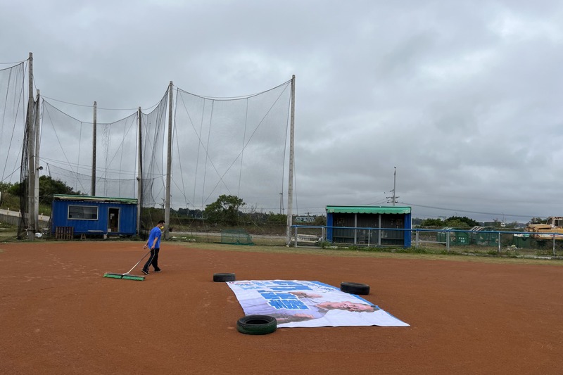 很多棒球場使用選舉看板帆布覆蓋投手丘，避免雨淋濕滑。記者林佩均／攝影
