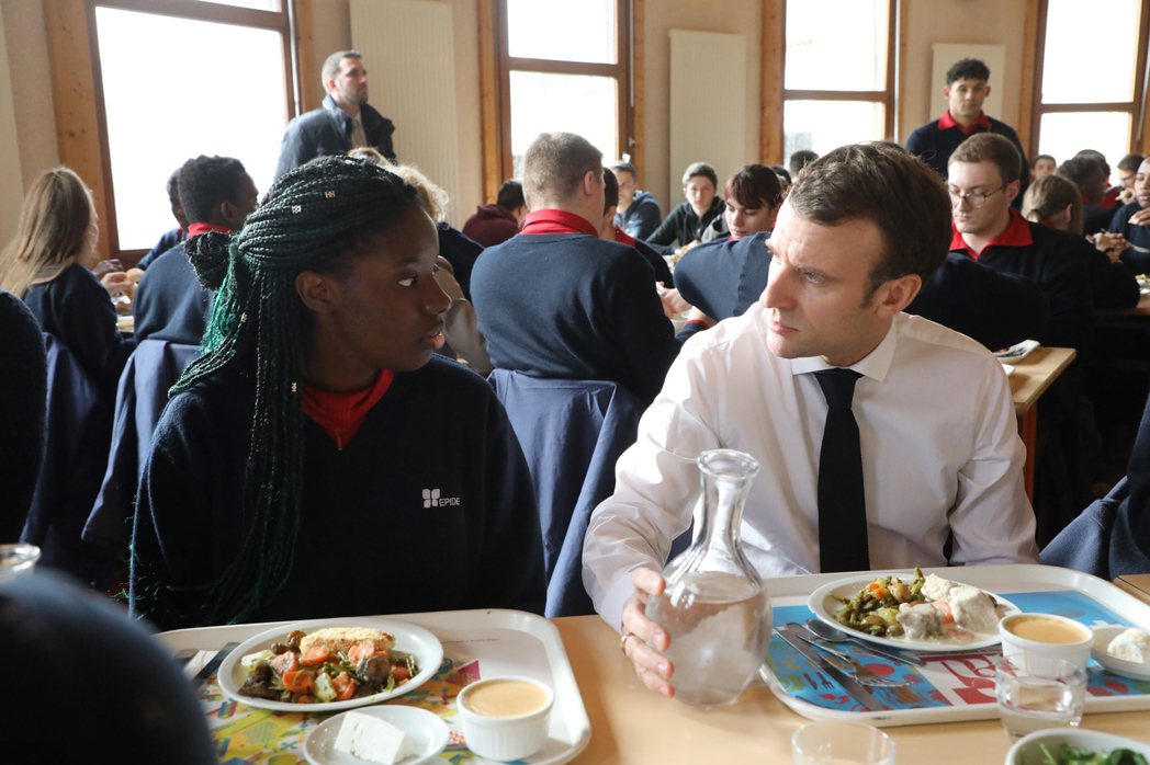 法國總統馬克宏（右）與學生於學生餐廳用餐。 圖／歐新社　