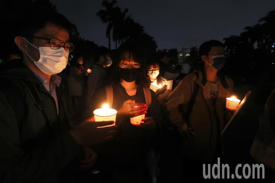 台大今晚舉行燭光悼念會，參加學生點燃燭光，手拿白紙，在雨中為烏魯木齊大火逝世者默...