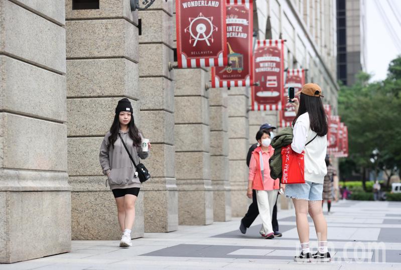 台灣自12月起解除戶外戴口罩規定，信義商圈逛街民眾在拍照時脫下口罩。記者余承翰／攝影