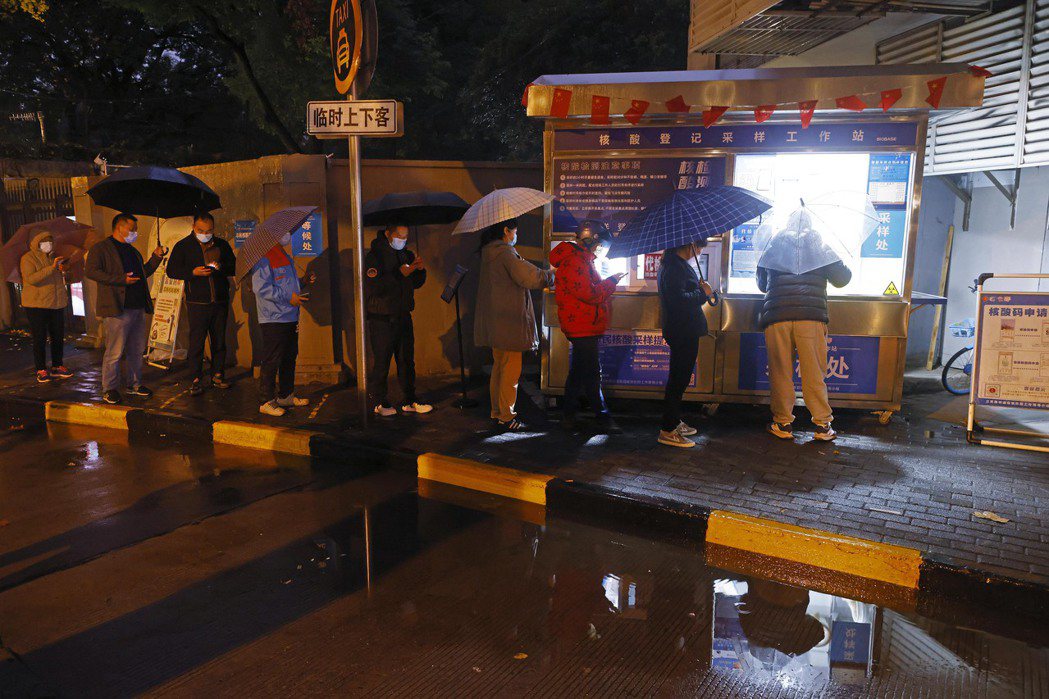 上海宣布進出開放式公共場所與搭乘公共交通不再查驗核酸。圖為早前上海市民冒雨進行核...