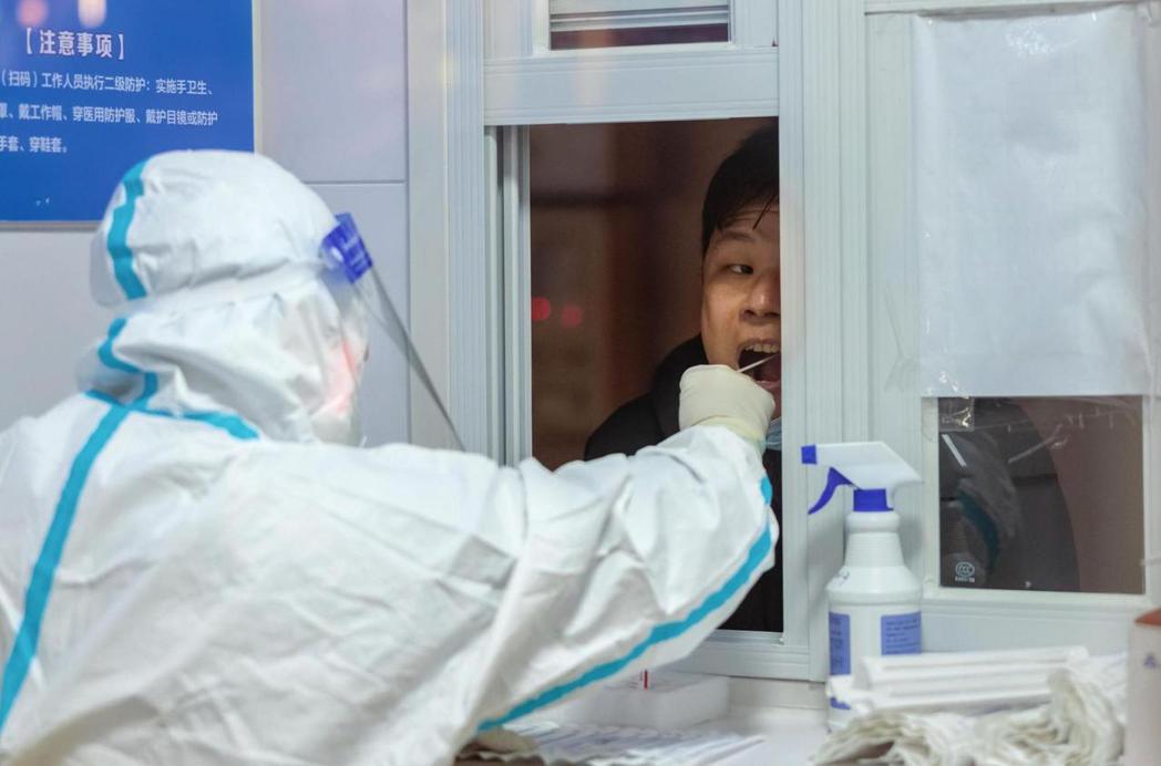 2022年11月，上海一名男子在核酸採檢站接受「大白」進行採檢。 圖／歐新社　