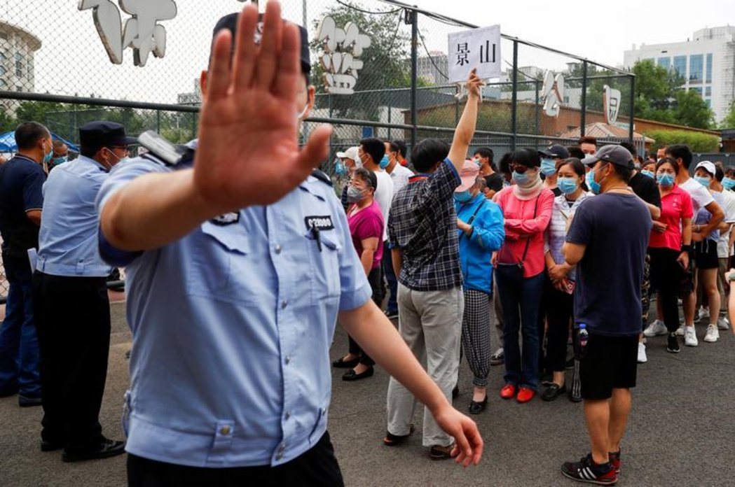 2020年6月，北京居民排隊等候接受核酸檢測，一名警員抬手示意攝影師不要拍攝。 ...