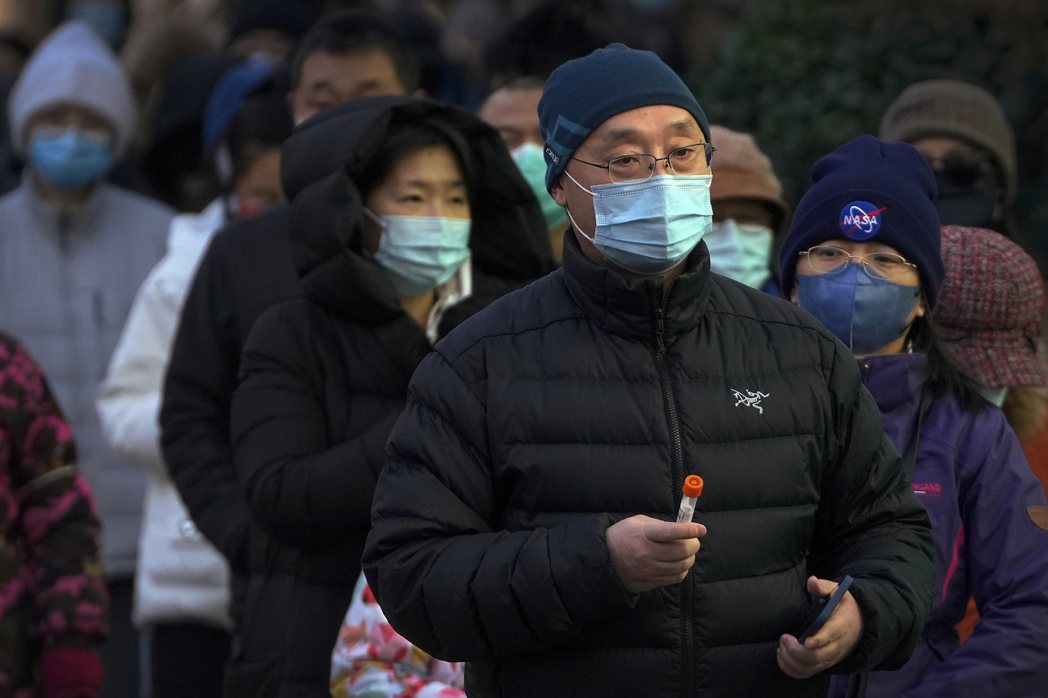 2022年12月，手拿裝有拭子的試管，等待做核酸的北京民眾。 圖／美聯社　