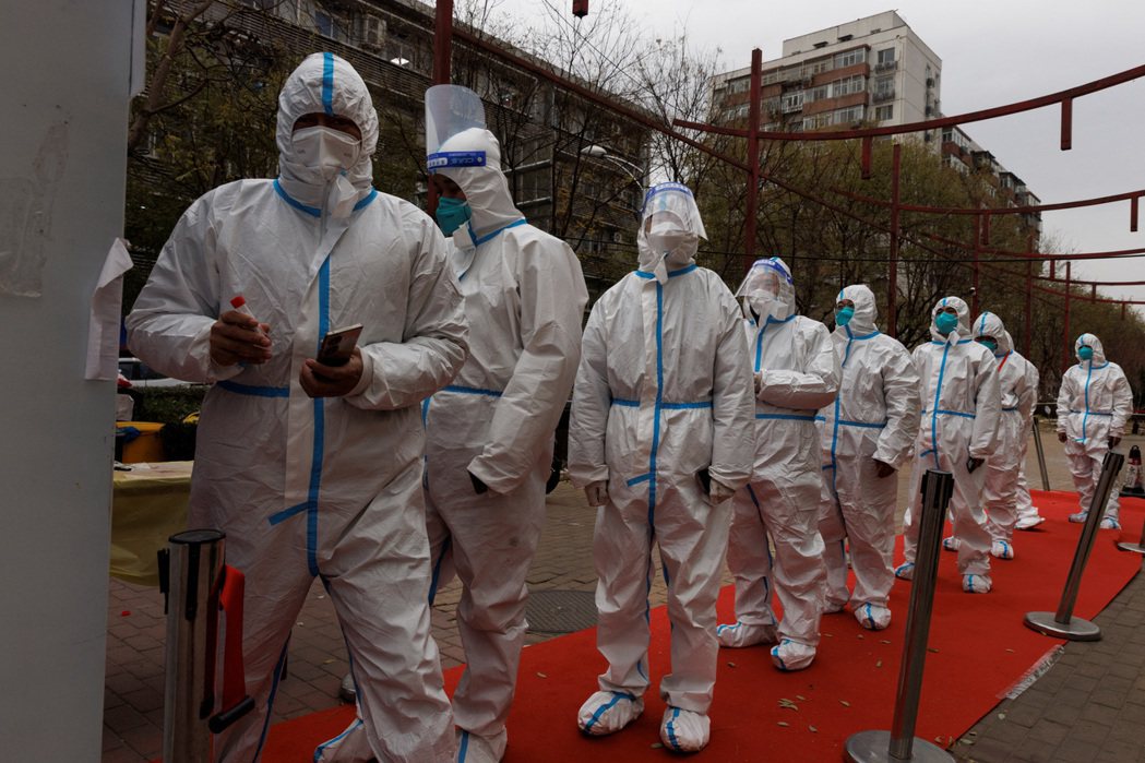 在北京排隊等著做核酸檢測的防疫人員「大白」。 圖／路透社
