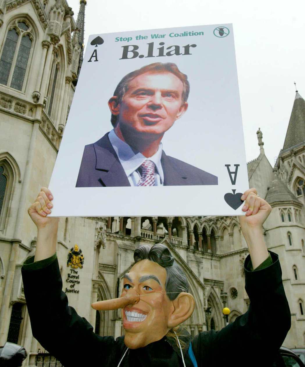 2003年8月，英國皇家法庭聽證會外，反戰示威者戴上布萊爾的面具、舉牌指責布萊爾...